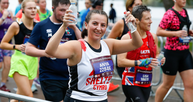 Woman running in an event, wearing a Shelter Cymru vest in support of the charity.