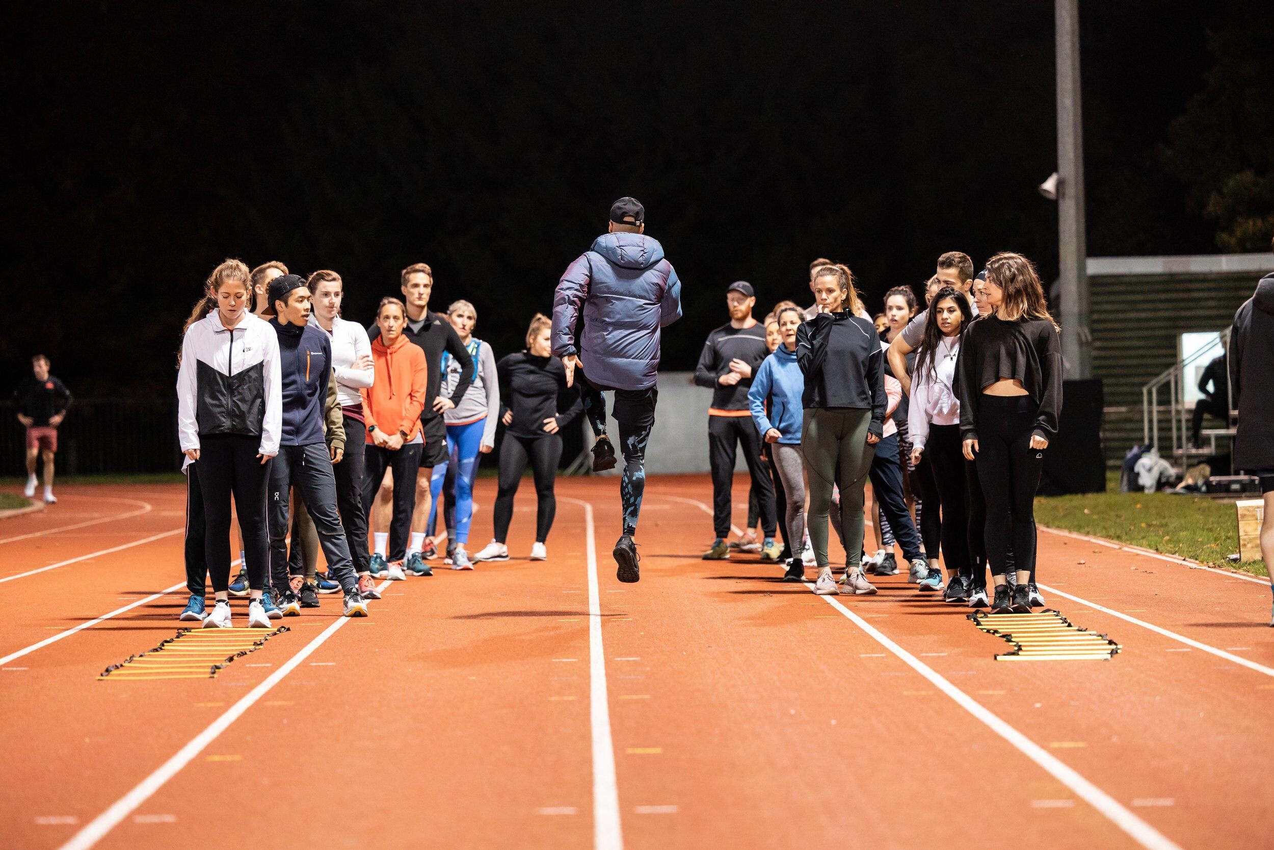 Athletes training on a track in the dark.