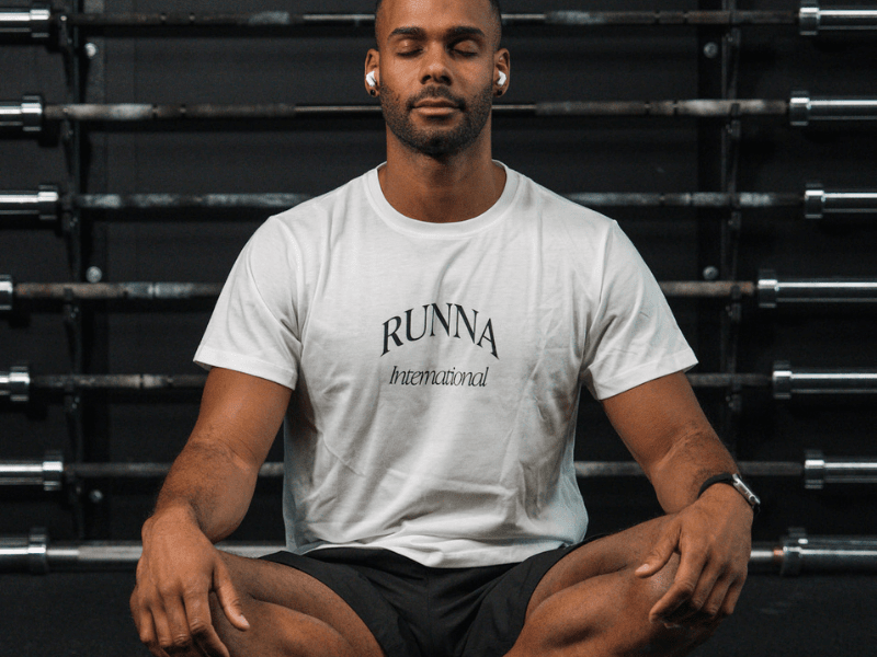 man in a Runna t-shirt sat cross-legged during mindful recovery.